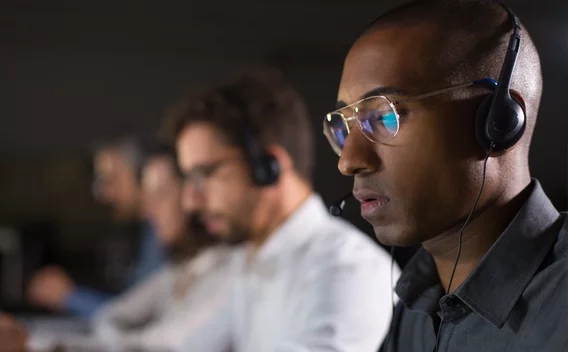 Man wearing glasses and headphones looking at a computer screen