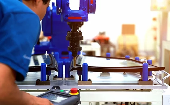 Man holding device looking closely at an automated robotic arm