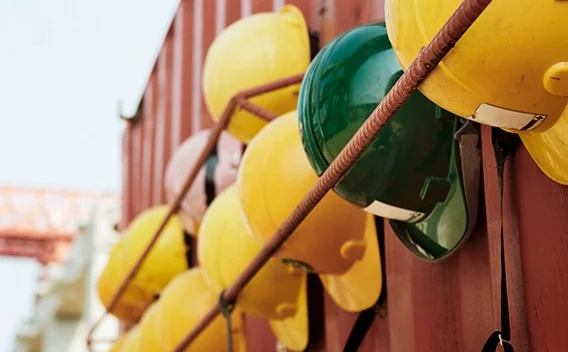 Yellow hard hats and a green hard hat hanging on the side of a shipping container