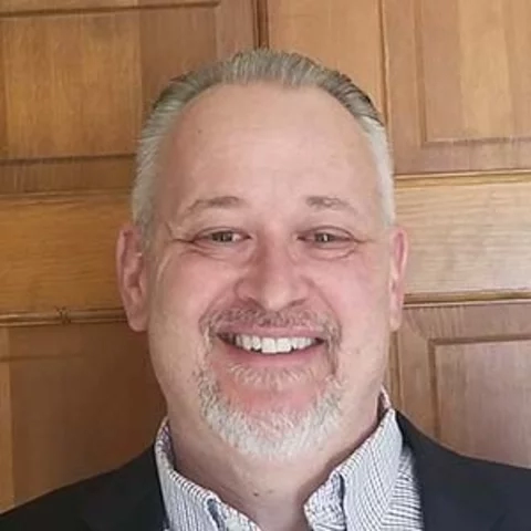 Man smiling wearing a suite and tie outside